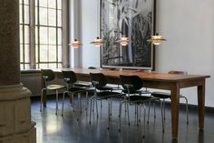 a long table with six chairs in front of it and a large painting on the wall