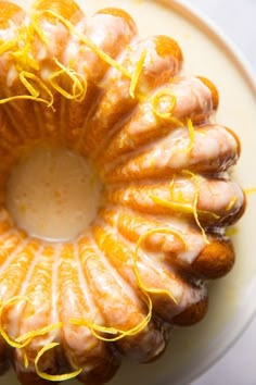 a bundt cake with icing and orange peels on the top is sitting on a plate