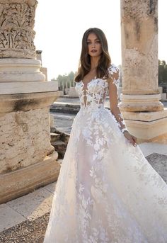 a woman in a wedding dress standing near columns