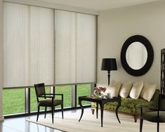 a living room filled with furniture next to a large window covered in white curtains and blinds