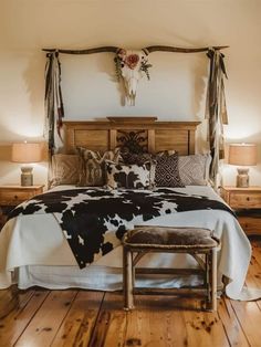 a bedroom with a cow print blanket on the bed and two nightstands next to it