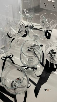 there are many glass bowls on the table with black ribbon around them and one is empty