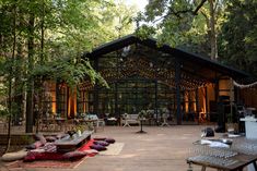 a wooden deck with lots of furniture and lights on top of it in the woods