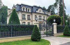 a large house that is next to a fence and some bushes in front of it