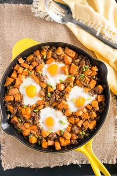 two fried eggs on top of sweet potatoes in a skillet