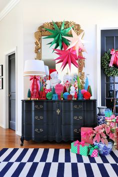 christmas presents are piled on top of an old dresser in the entryway to a home