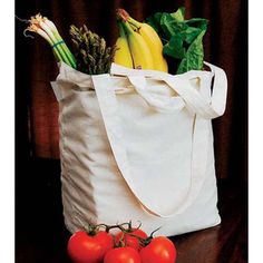 a white bag filled with tomatoes, bananas and other vegetables sitting on top of a wooden table