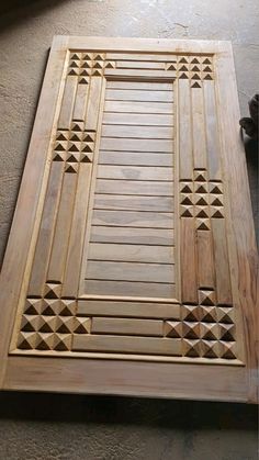 an unfinished wooden door with geometric designs on the outside and inside is being worked on