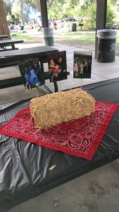 hay bale cake sitting on top of a red table cloth with pictures in the background