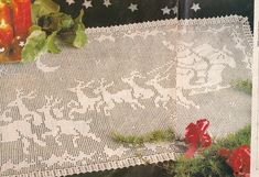 a table cloth with the words merry christmas written on it next to candles and greenery