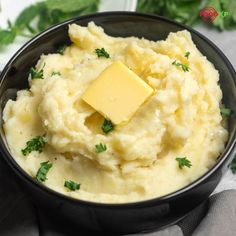 mashed potatoes with butter and parsley in a black bowl on a gray napkin