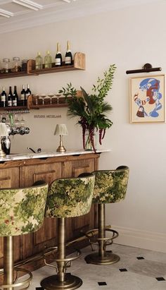 two bar stools sitting in front of a counter with bottles on it