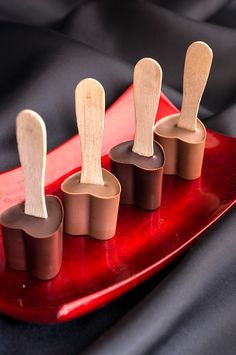 four wooden spoons sitting on top of a red tray