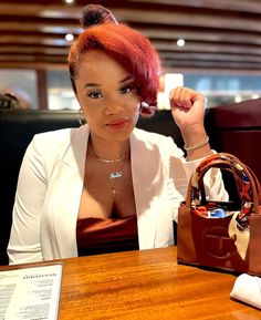 a woman sitting at a table with a purse and cell phone in front of her