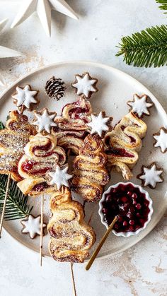 some cookies and other food on a plate next to pine cones, christmas decorations and fir tree branches