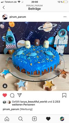 the cake is decorated with blue icing and space themed decorations on top of it