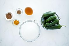 the ingredients to make green chili are in bowls and next to each other on a white surface