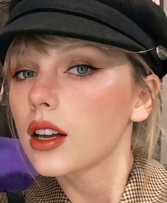 a close up of a person wearing a hat and blue eyes with an orange lip