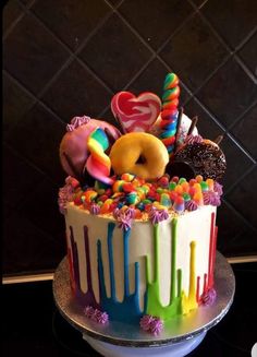 a multicolored cake with donuts and candy on top