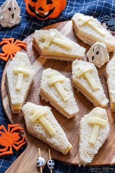 several sandwiches with cheese on them are sitting on a wooden board next to halloween decorations