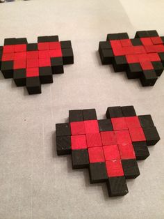 three pieces of wood that have been made to look like heart shaped blocks with red and black squares on them