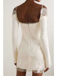 the back of a woman's white dress with long sleeves and an open shoulder