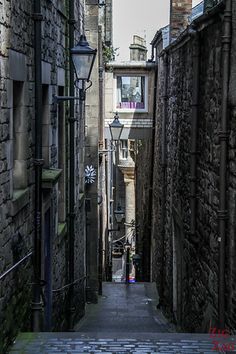 an alley way with stone buildings and cobblestone walkway leading up to the street