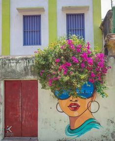 a painting on the side of a building with flowers growing out of it's head