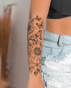 a woman's arm with flowers and butterflies tattooed on her left arm, in front of a mirror