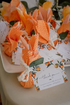 orange and white paper flowers are on a table with place cards for guests to sign