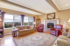 a living room with couches, chairs and a rug in front of a fire place