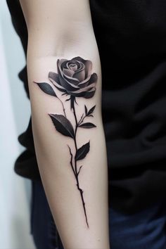 a woman's arm with a black rose tattoo on the left side of her arm