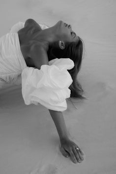 a woman laying on the sand in a white dress