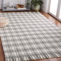 a white and grey rug with fringes on the floor in front of a window