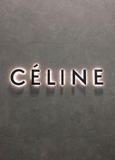 the word celine is lit up in black and white letters on a gray wall