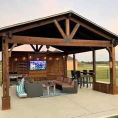 an outdoor living area with couches, chairs and a flat screen tv on the wall