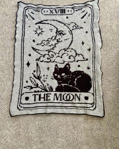 a black and white cat sitting on top of a pillow with the moon above it