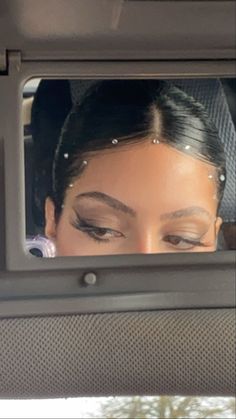 a woman's eyes are reflected in the rear window of a vehicle as she sits