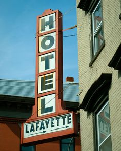 the hotel lafayette sign is hanging from the side of a building in front of a brick building