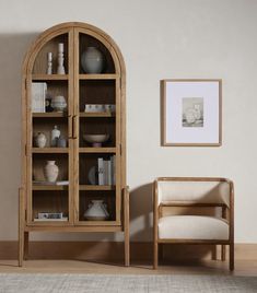 a wooden book case sitting next to a white chair in a room with beige walls