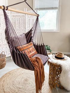 a hammock hanging from a wooden pole in a room with white walls and rugs