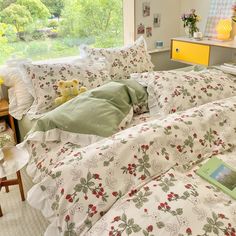 a bed with white and green comforters in a bedroom next to a window overlooking trees