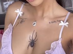 a close up of a woman with tattoos on her chest and spider on her shoulder