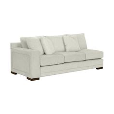 a white couch with four pillows on it's back and one arm facing the camera