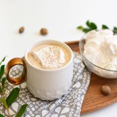 there is a cup of coffee with whipped cream in it on the tray next to nuts