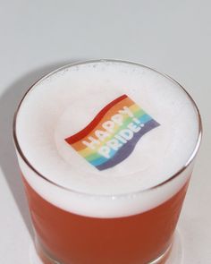 a close up of a drink in a glass with a rainbow sticker on it