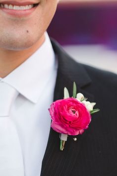 a man in a suit with a pink flower on his lapel