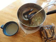 a person is stirring some food in a pot on the table next to a cup