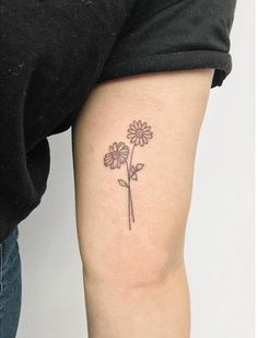 a woman's arm with a small flower tattoo on the left side of her leg