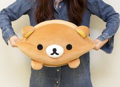 a woman holding a brown teddy bear pillow